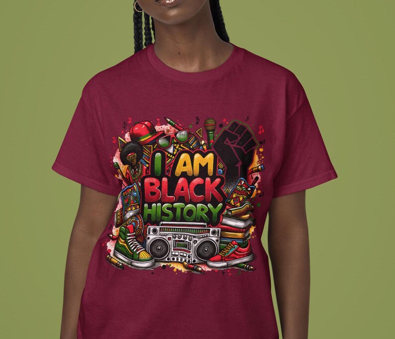May include: A maroon t-shirt with a colorful graphic design featuring the text "I AM BLACK HISTORY". The design includes a raised fist, books, a boombox, and other objects.