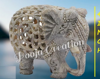 Puede incluir: Una figurita de elefante tallada en piedra con detalles intrincados. El elefante mide 10 cm de alto y tiene un color gris claro. La figurita está hecha de esteatita y tiene un diseño delicado y calado.