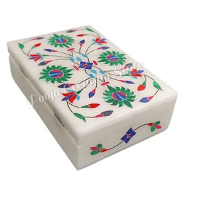 Pode incluir: Caixa de mármore branco com um design floral incrustado com pedras coloridas. O design apresenta flores verdes, azuis, vermelhas e rosas.