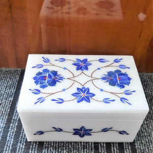 May include: White marble box with intricate blue and red floral designs inlaid on the lid and front. The box is closed.