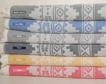 May include: A stack of six patterned Turkish towels in various colors, including dark green, sax blue, gray, navy, yellow, and pink. The towels feature a geometric design and are made of cotton.