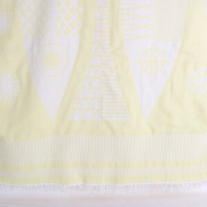 May include: A light yellow and white patterned beach towel. The towel features geometric shapes and designs in white against a yellow background. The bottom edge has a fringe.