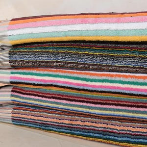 May include: A stack of five striped towels in various colors, including pink, orange, yellow, green, blue, and brown. The towels are labeled "Multicolor 1", "Multicolor 2", "Multicolor 3", "Multicolor 4", and "Multicolor 5".