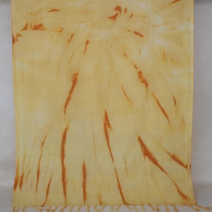 May include: A yellow and orange tie-dye scarf with a fringed edge.