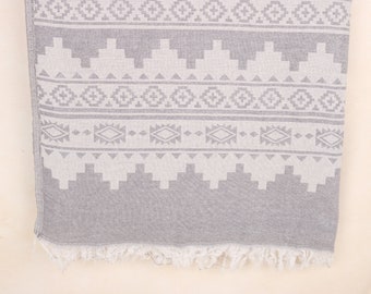Peut inclure: Une serviette à motifs gris et blancs avec un motif géométrique. La serviette présente un motif répétitif de losanges, de triangles et d'autres formes. Le bord inférieur est orné de franges.