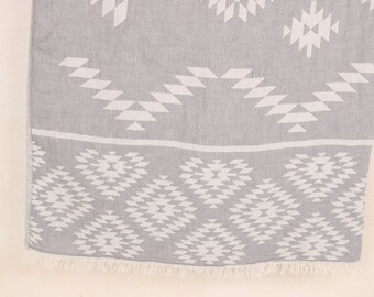 May include: A gray and white patterned textile with a geometric design. The fabric features a repeating pattern of white shapes on a gray background. The bottom edge has a fringe.