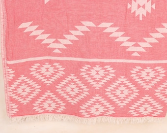 Puede incluir: Un textil estampado en rojo y blanco con un diseño geométrico. La tela presenta un patrón repetitivo de formas de diamantes y triángulos blancos sobre un fondo rojo. El borde inferior tiene una franja blanca.