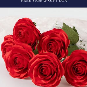 May include: Six handmade red roses are displayed, showcasing their vibrant color and intricate petal details. The image includes text at the top that reads "SIX HANDMADE ROSES FREE VASE & GIFT BOX". The roses are arranged on a white surface.