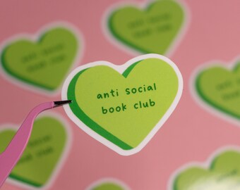 May include: Green heart-shaped sticker with the text "anti social book club" on a pink background.