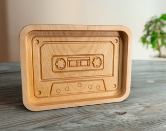 May include: A wooden tray with a carved cassette tape design. The tray is light brown and has a smooth, polished finish.