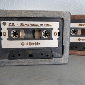 May include: Two wooden cassette tape boxes with a black and white cassette tape design. The left box has the text "Z.B. - SOMETHING IN THE..." and a heart symbol. The right box has the text "OUR SONG".