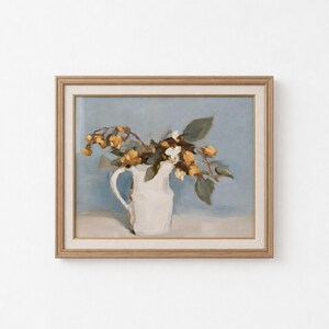 Op de afbeelding: Een ingelijst olieverfschilderij met een witte keramische kan gevuld met gele bloemen en groene bladeren tegen een zachte blauwe achtergrond. Het kunstwerk zit in een lichtgekleurde houten lijst met een neutrale passe-partout rand.