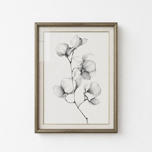 May include: A framed wall art piece featuring a black and white pencil sketch of a flowering branch with delicate, rounded petals. The artwork is encased in a textured, metallic bronze-toned frame with a wide, off-white mat border.