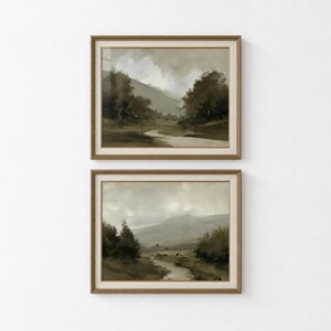以下が含まれることがあります： 茶色、ベージュ、グレーの落ち着いたアースカラーで描かれた2枚の額入り風景画。どちらの絵も、曇り空の下、暗い木々と遠くのなだらかな丘に囲まれた、草地を抜ける曲がりくねった小道が描かれています。