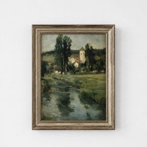 May include: A framed landscape painting featuring a winding river flowing through a green meadow toward a small village with a church tower. The scene is rendered in muted earth tones and deep greens, enclosed in a textured, metallic silver frame.