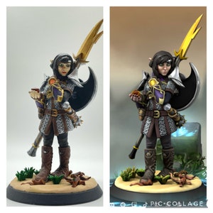 May include: A hand-painted miniature figurine of a female elf warrior holding a small, glowing orb. She is wearing dark purple and silver armour with a black cape and a golden belt. She is holding a spear with a lightning bolt design and a black axe. The figurine is standing on a sandy base with green plants and brown branches.