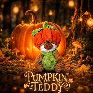 Puede incluir: Un oso de peluche tejido a ganchillo con un sombrero de calabaza naranja brillante con tallo verde y un mameluco verde. El oso tiene pelaje marrón, hocico blanco y ojos negros. El texto PUMPKIN TEDDY aparece abajo en fuente decorativa.