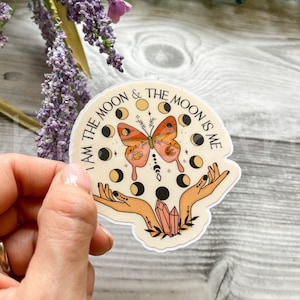 May include: A white sticker with a pink and orange butterfly, a crescent moon, and the text "I am the moon & the moon is me".