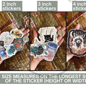 May include: A size guide for stickers showing different sizes of stickers. The stickers feature various designs, including a cat with the text "Life is better with cats & books", a raccoon with mushrooms, and a potted plant with the text "I run on hot tea and books". The guide shows 2 inch, 3 inch, and 4 inch stickers.