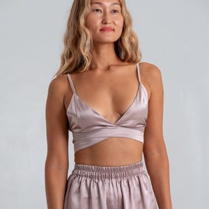 Peut inclure: Ensemble de vêtements de nuit assortis de couleur mauve clair. Le haut est un bralette délicat avec de fines bretelles et un design croisé. Le bas est un short taille haute avec une taille élastique. Le tissu a un éclat subtil, suggérant du satin ou de la soie.