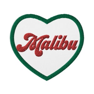 以下が含まれることがあります： 緑色の縁取りのある白いハート型のワッペンで、赤い糸で「マリブ」と刺繍されています。