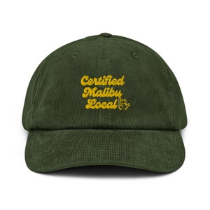 May include: A green corduroy baseball cap with the text "Certified Malibu Local" embroidered in yellow.