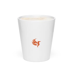 May include: White ceramic coffee cup with a light brown beverage inside. The cup features a small orange phoenix logo on the side. The cup has a smooth, clean design, suitable for hot or cold drinks.