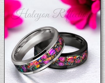 May include: Two wedding bands with a black and silver finish. The bands are inlaid with colorful, iridescent opal-like material.