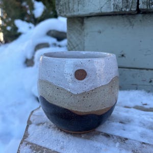 Taza de cerámica con forma de montaña y cielo nevado