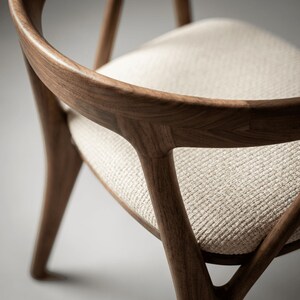 May include: A wooden chair featuring a curved backrest and a light beige textured fabric seat. The frame is constructed from dark brown wood with visible grain patterns, showcasing a rounded design that connects the backrest to the seat base.