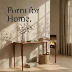 May include: A wooden console table with four tapered legs, featuring a clear glass vase with bare branches, a small rectangular tray, and stacked books on top. The wall displays the dark grey text Form for Home. A woven basket sits below.