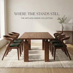 May include: A rectangular wooden dining table with four thick legs and six chairs featuring curved wooden frames and dark green upholstered seats. The wall above displays the text: WHERE TIME STANDS STILL. THE ARTLAND DINING COLLECTION.