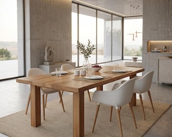 Puede incluir: Una mesa de comedor rectangular de madera con cuatro patas gruesas, rodeada de cuatro sillas blancas con patas de madera clara. La mesa está puesta con platos blancos, vasos transparentes, cuencos pequeños y un jarrón de cristal.