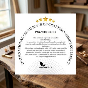 May include: A certificate of craftsmanship from 1996 Wood Co. is displayed on a wooden surface. The certificate features gold stars and text that highlights the company's dedication to quality and craftsmanship. The company logo is at the bottom.