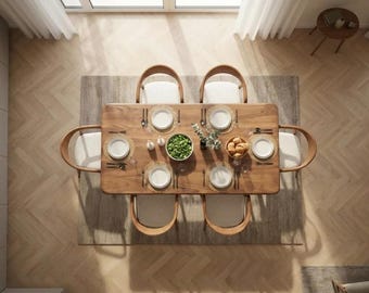 Op de afbeelding: Luchtfoto van een eettafel voor zes personen. De rechthoekige houten tafel is omringd door zes stoelen met lichtgekleurde kussens. Elke plaatsing heeft een wit bord, bestek en een decoratieve placemat. Een kom salade en brood staan in het midden.