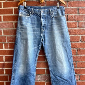 Op de afbeelding: Een lichtblauwe spijkerbroek met knoopsluiting en een verweerde look. De broek heeft een rechte pijp en een ontspannen pasvorm.