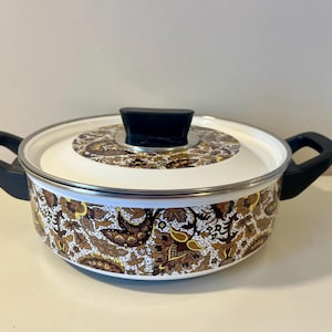 May include: A vintage cooking pot with a white lid and a black handle. The pot features a brown and white floral pattern. The pot is approximately 25 cm in diameter and 13 cm tall.