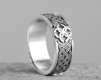 May include: A silver ring with a Celtic knot design. The ring is wide and has a raised design.