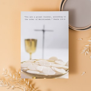 Può includere: Una fotografia con una carta bianca con il testo "Tu sei sacerdote per sempre, secondo l'ordine di Melchisedec." Salmo 110:4. La carta è posta davanti a uno sfondo sfocato con una croce, un calice e ostie.