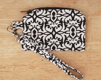 May include: A black and white patterned fabric zippered pouch with a black fabric strap. The pouch has a black zipper and a black and white patterned strap.
