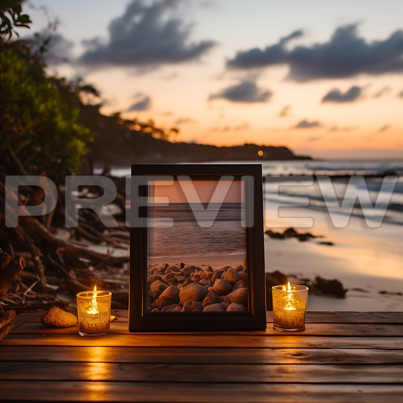 May include: A framed photograph of a beach scene with rocks and water, sitting on a wooden surface with two lit candles on either side.