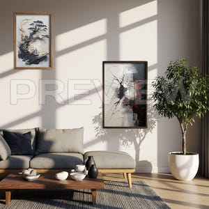 May include: Two framed abstract art pieces hang on a white wall above a gray sofa and wooden coffee table. One features a tree, the other a black, white, and red design. A potted plant sits to the right, and sunlight streams across the room.