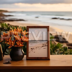 May include: A wooden picture frame with a brown mat and a photo of a beach with rocks and the text "In every walk with nature one receives far more than he seeks." The frame is sitting on a wooden table with a vase of orange flowers in front of it.