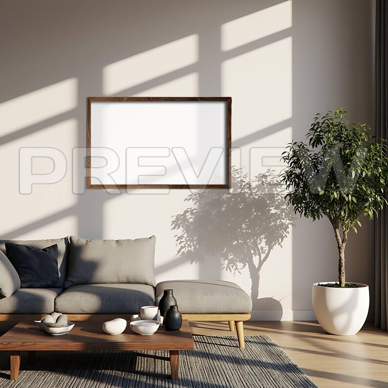 May include: A rectangular wooden framed blank canvas hanging on a white wall. The room features a gray sofa, a wooden coffee table with decorative bowls and vases, and a potted plant. Sunlight casts shadows across the scene.