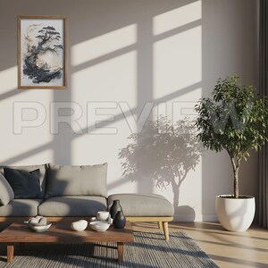 May include: A framed artwork featuring a stylized black and white tree landscape. The artwork is in a wooden frame and hangs on a white wall. The room includes a gray sofa, a wooden coffee table, and a potted plant.
