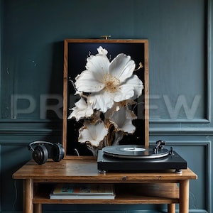 Op de afbeelding: Een houten tafel met een platenspeler, een boek en een ingelijste print van een witte bloem met gouden accenten. De print is tegen een donkere achtergrond.