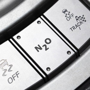 May include: Close-up of a silver car dashboard with three buttons. The buttons are labeled "N2O", "OFF", and "TRACK".