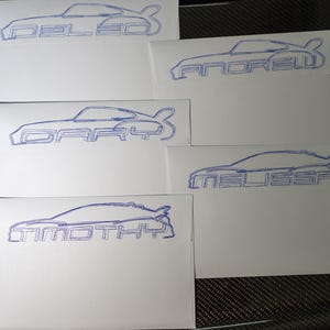Pu&ograve; includere: Biglietti bianchi con contorni blu di auto e nomi: "DELEO", "ANDREW", "GARY", "MELISSA" e "TIMOTHY". Il design dell'auto &egrave; una coup&eacute;. I biglietti sono disposti su una superficie scura e strutturata.