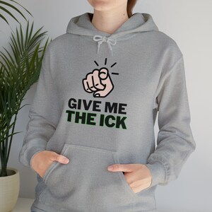 May include: A light gray hoodie with a front pocket and a drawstring hood. The graphic on the front features a pointing hand with the text "GIVE ME THE ICK" in black and green.