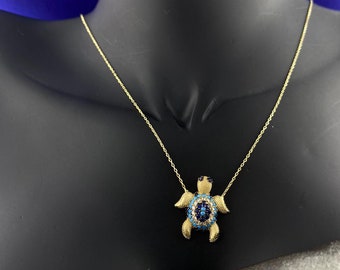 May include: Gold necklace with a turquoise and blue evil eye turtle pendant.